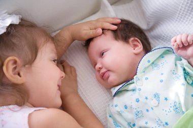 İki küçük kız kardeş beşiğinde uzanıyor ve tatlı tatlı sohbet ediyorlar.