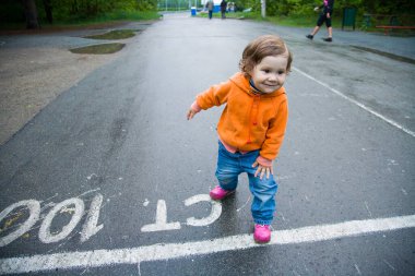 Kırmızı ceketli küçük kız koşu bandının başında duruyor.