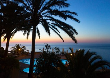 Günbatımında sakin bir denizde tropikal bir tatil köyünde güzel bir ufuk manzarası.