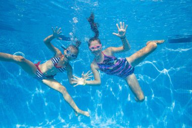 İki küçük kız havuzda su altında oynuyor..