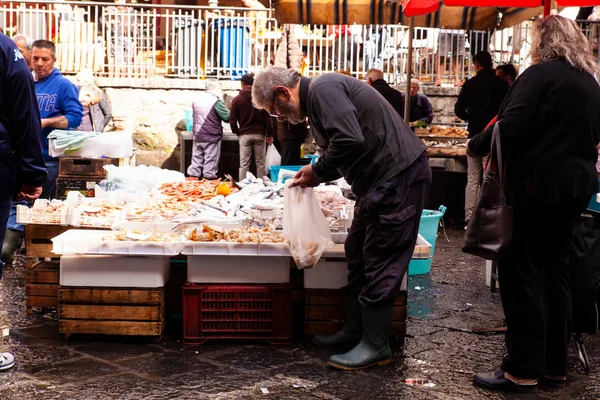 Venditore accanto alla sua bancarella di pesce mettendo nella borsa cicale di mare — Foto Stock