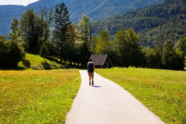 Sırt çantalı genç bir kadın Slovenya kırsalında yürüyüş yapıyor. Bohinj