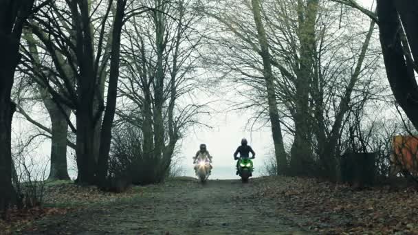 Motociclistas, um cara e uma menina, passando pela floresta . — Vídeo de Stock