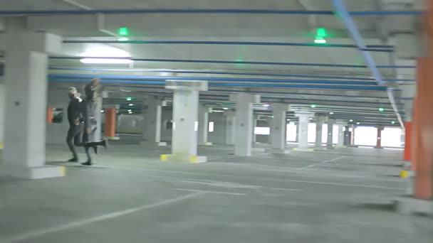 Una giovane coppia corre attraverso il parcheggio . — Video Stock