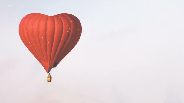 Globo de aire caliente rojo forma de corazón volar en pueblo de invierno — Vídeo de stock