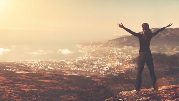 Silhouette de jeune femme avec bras levés debout sur le sommet de la montagne — Video