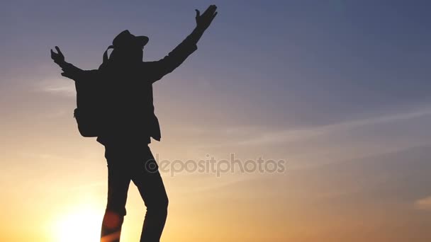 Silhouette di un uomo con uno zaino contro il tramonto del cielo luminoso — Video Stock