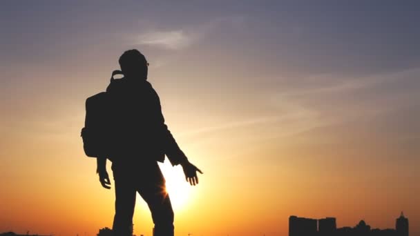 Silhouet van een man met een rugzak tegen heldere hemel, zonsondergang — Stockvideo