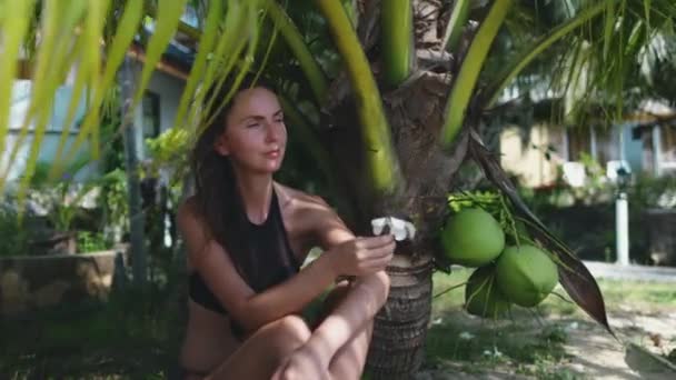 Beautiful carefree woman sit under palm tree leaf — Stock Video