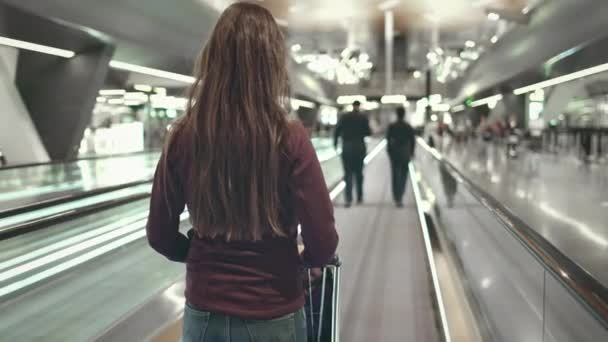 Frau mit Gepäck steht auf Rolltreppe am Flughafen — Stockvideo