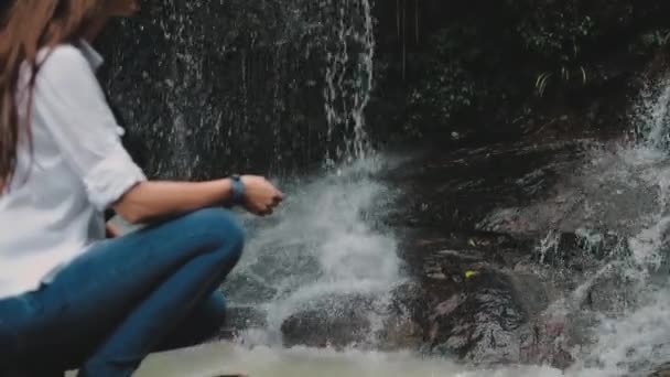 Menina caminhante agachar perto de cachoeira floresta tropical — Vídeo de Stock