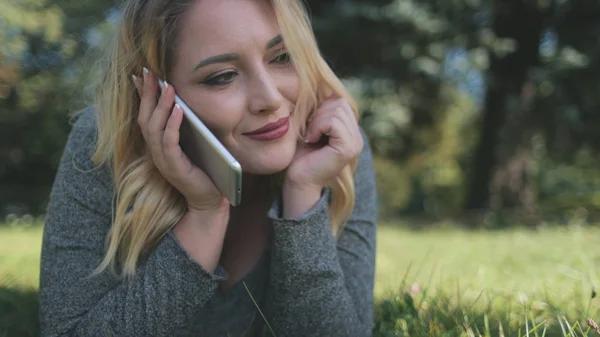 Menina bonita Smartphone falar mentira no gramado verde — Fotografia de Stock