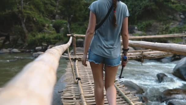 Woman on bridge over fast mountain river thailand — Stockvideo