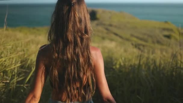 Молодая женщина, идущая к краю скалы Банава — стоковое видео