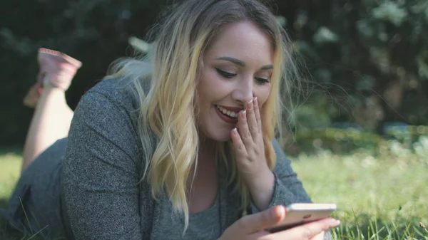 Chica feliz Navegar Smartphone mentira en el césped verde — Foto de Stock
