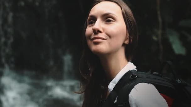 Happy woman look at splashing waterfall in jungle — Stock video