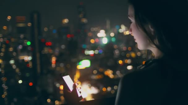 Agradable dama celebrar teléfono inteligente noche paisaje urbano azotea — Vídeos de Stock