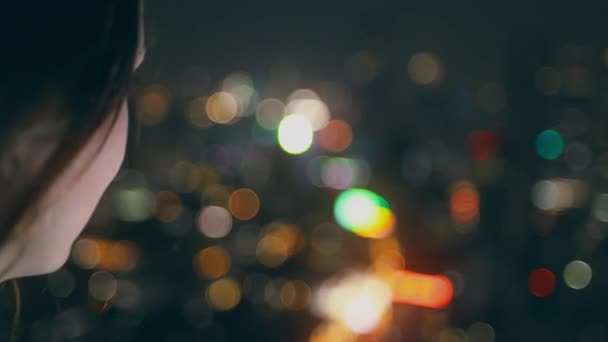 Mujer joven mira la noche metrópolis vista en la azotea — Vídeos de Stock
