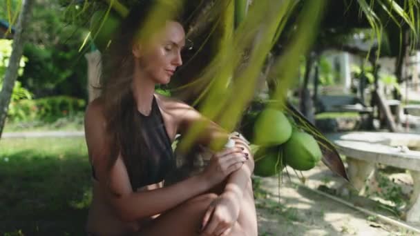 Καυκάσια γυναίκα που κάθεται κάτω από φοίνικα καρύδας — Αρχείο Βίντεο