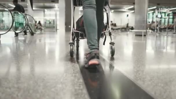 Vrouw dragen bagage kar lopen op luchthaven terminal — Stockvideo