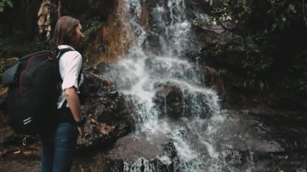 Chica mochilero disfrutar de cascada en selva — Vídeo de stock
