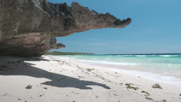 Prumo rochoso lançando sombra na areia perto da costa — Vídeo de Stock