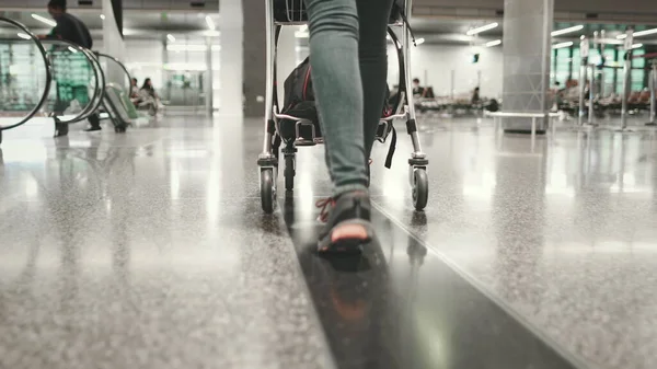 Жінка несе багажний візок прогулянка в терміналі аеропорту — стокове фото