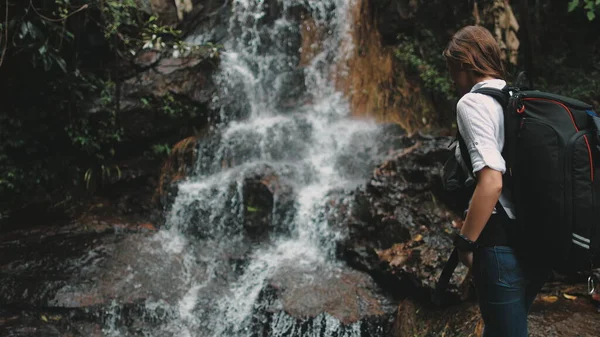 Touristin greift nach plätscherndem Wasserfall — Stockfoto