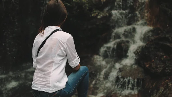 Mujer turista mirada en salpicaduras de cascada tropical —  Fotos de Stock