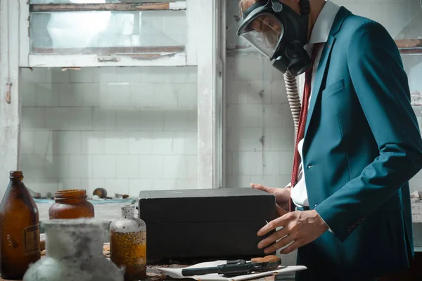 De foto van de mens in gasmasker met koffer. in de koffer gekiemde tarwe — Stockfoto