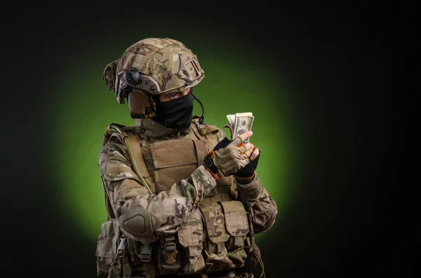 Ein Soldat in Militärkleidung mit Waffe auf dunklem Hintergrund mit Geld — Stockfoto
