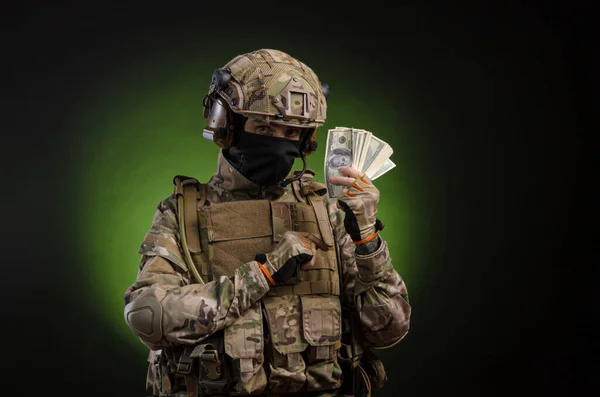 a male soldier in military clothes with a weapon on a dark background with money