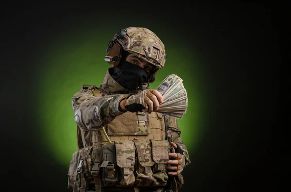 Żołnierz w wojskowych ciuchach z bronią na ciemnym tle z pieniędzmi — Zdjęcie stockowe