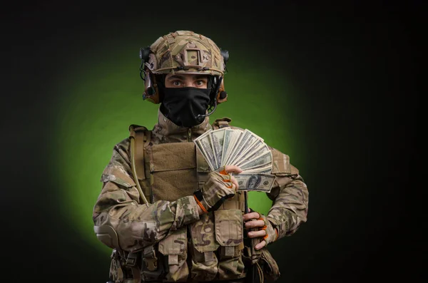 Ein Soldat in Militärkleidung mit Waffe auf dunklem Hintergrund mit Geld — Stockfoto