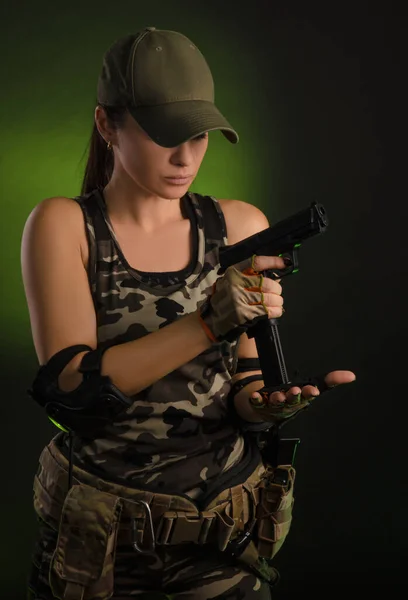 The girl in military overalls airsoft posing with a gun in his hands on a dark background in the haze — Stock Photo, Image