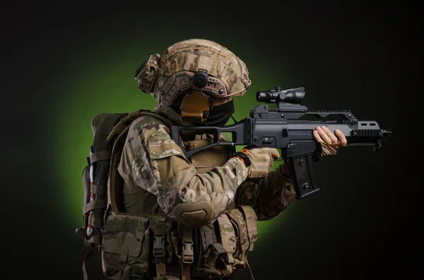 Чоловічий солдат у військовому одязі зі зброєю на темному тлі — стокове фото
