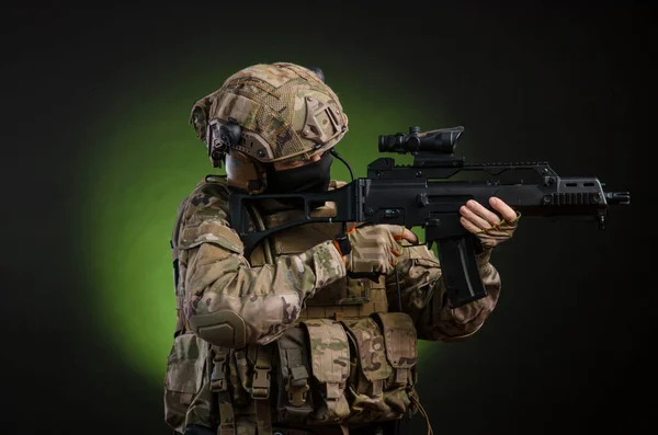 A male soldier in military clothes with a weapon on a dark background — Stock Photo, Image