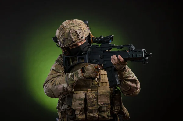 A male soldier in military clothes with a weapon on a dark background — Stock Photo, Image