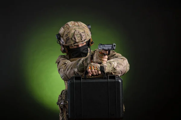 Um soldado masculino em roupas militares com uma arma em um fundo escuro — Fotografia de Stock