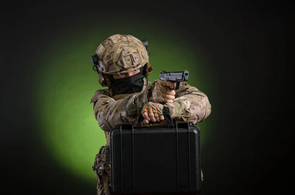 En manlig soldat i militära kläder med ett vapen på en mörk bakgrund — Stockfoto