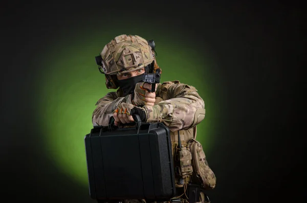 En manlig soldat i militära kläder med ett vapen på en mörk bakgrund — Stockfoto