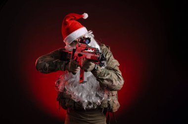 Silahlı ve Noel Baba şapkalı askeri üniformalı bir adam.