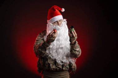 Silahlı ve Noel Baba şapkalı askeri üniformalı bir adam.