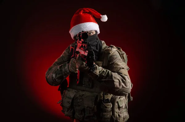Чоловік у військовій формі з пістолетом і капелюхом Санта Клауса. — стокове фото