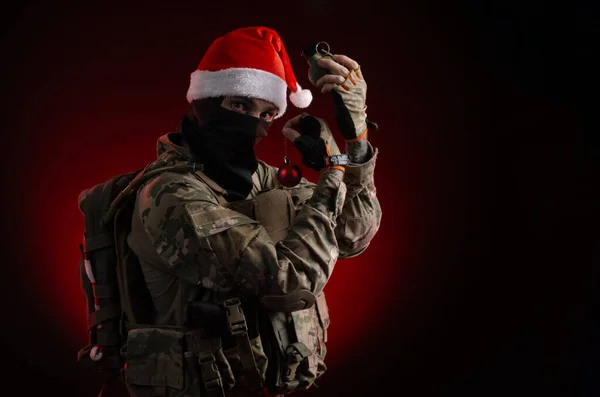 Um homem de uniforme militar com uma arma e um chapéu de Pai Natal — Fotografia de Stock