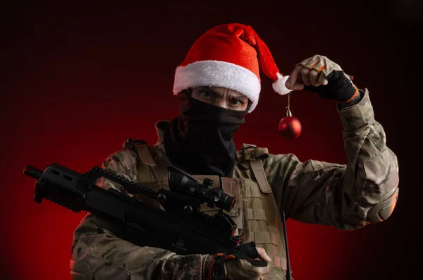 Чоловік у військовій формі з пістолетом і капелюхом Санта Клауса. — стокове фото