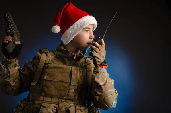 A teenager in a soldiers uniform and Santa Claus hat is talking on the radio — Stock Photo, Image