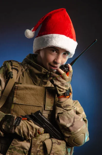 Um adolescente em um uniforme de soldados e chapéu de Papai Noel está falando no rádio — Fotografia de Stock