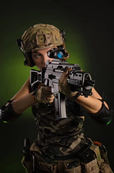 Het meisje in militaire overalls Airsoft poseren met een pistool in zijn handen op een donkere achtergrond in de Haze — Stockfoto