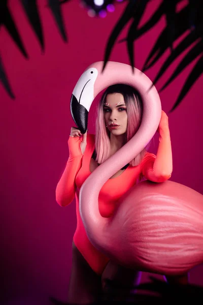 Parlak vücutlu bir kız büyük bir Flamingo heykelciğiyle poz veriyor. — Stok fotoğraf